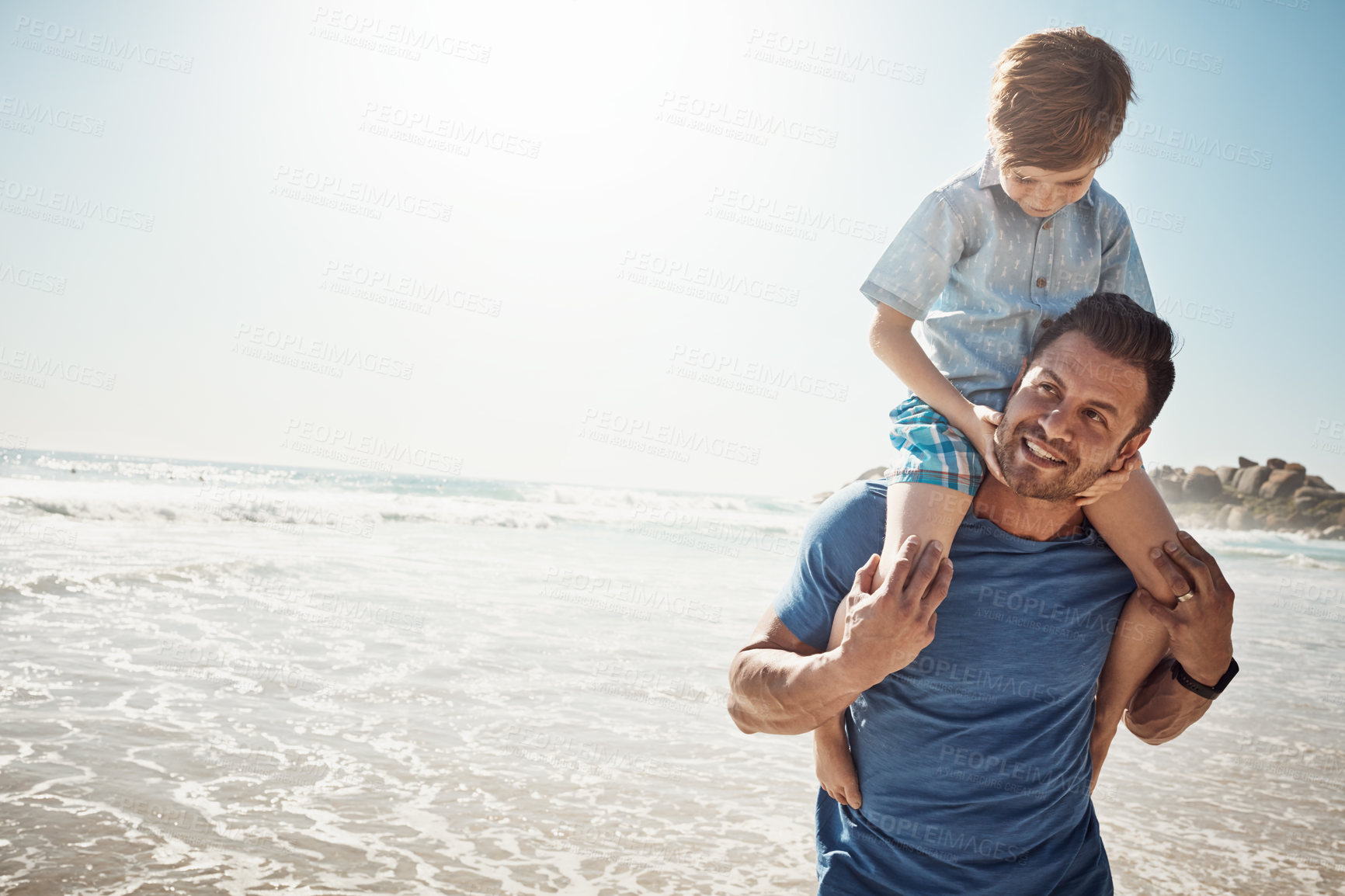 Buy stock photo Shot of a father carrying his little son on his shoulders at the beach