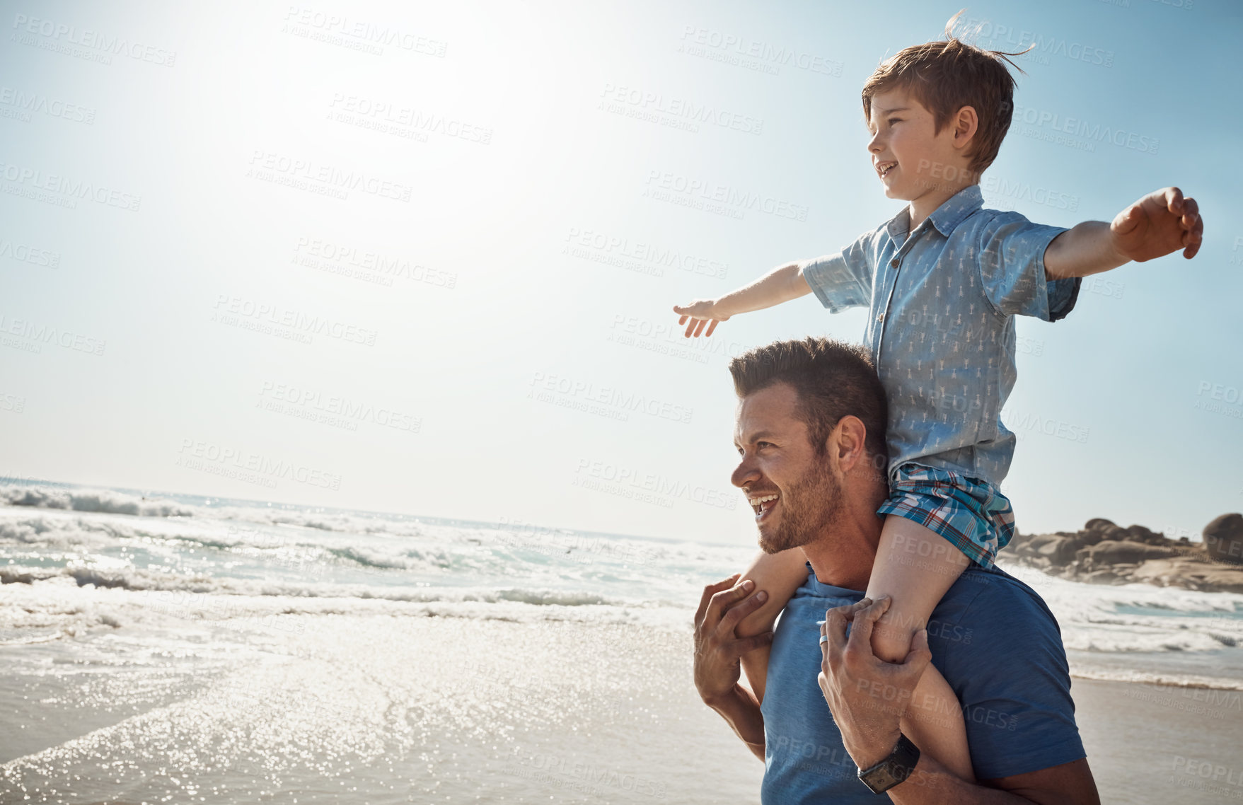 Buy stock photo Shot of a father carrying his little son on his shoulders at the beach