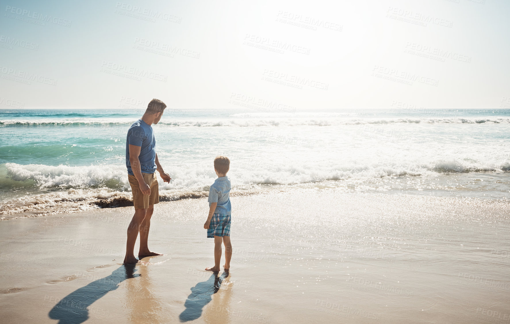 Buy stock photo Shot of a father and his little son bonding together at the beach