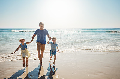 Buy stock photo Shot of a father bonding with his two little children at the beach