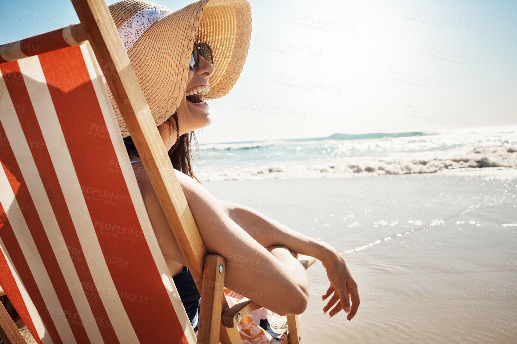 Buy stock photo Woman, laugh and sunglasses at beach with water, sand and relax for vacation by ocean in summer. Female person, smile and sunset on chair in Miami for tropical holiday, travel or peace with wellness