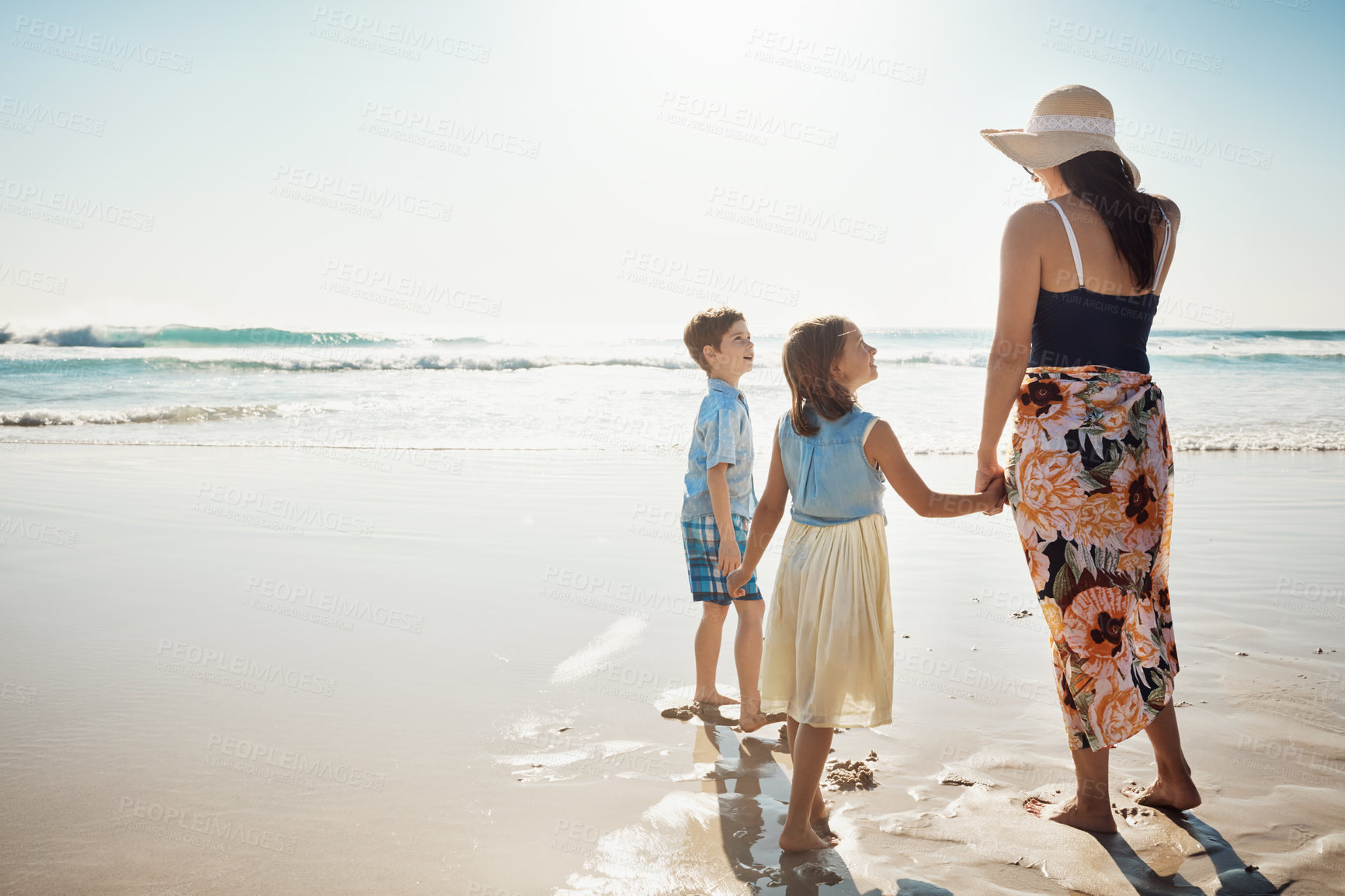 Buy stock photo Rear view shot of a mother bonding with her two little children at the beach