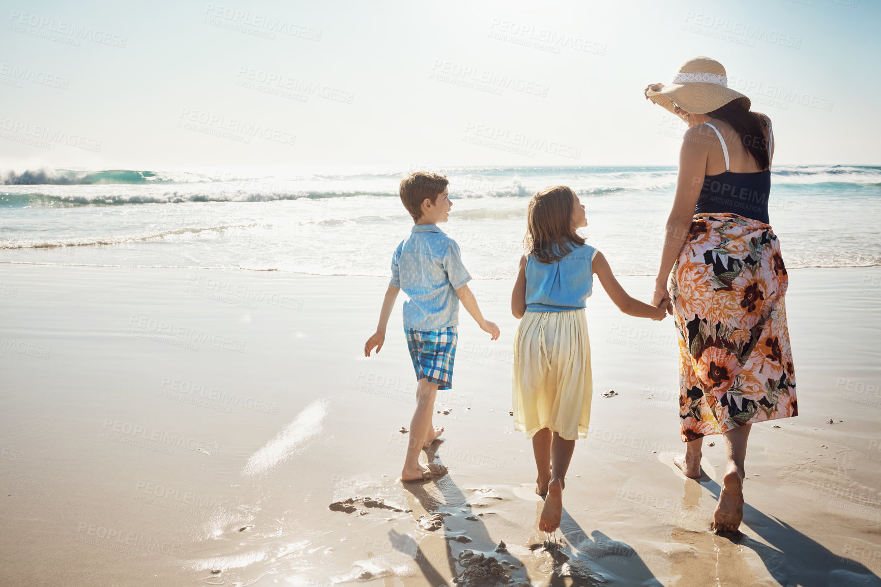Buy stock photo Rear view shot of a mother bonding with her two little children at the beach