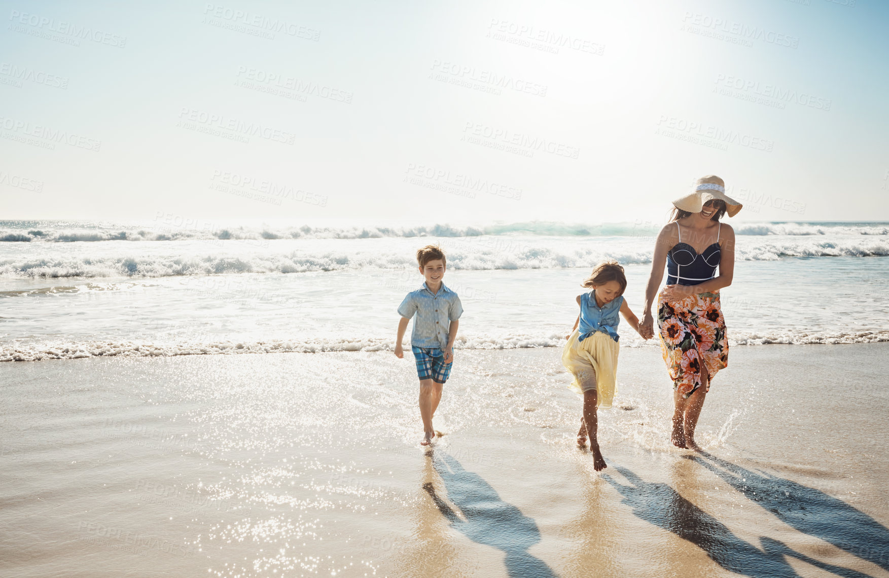 Buy stock photo Shot of a mother bonding with her two little children at the beach