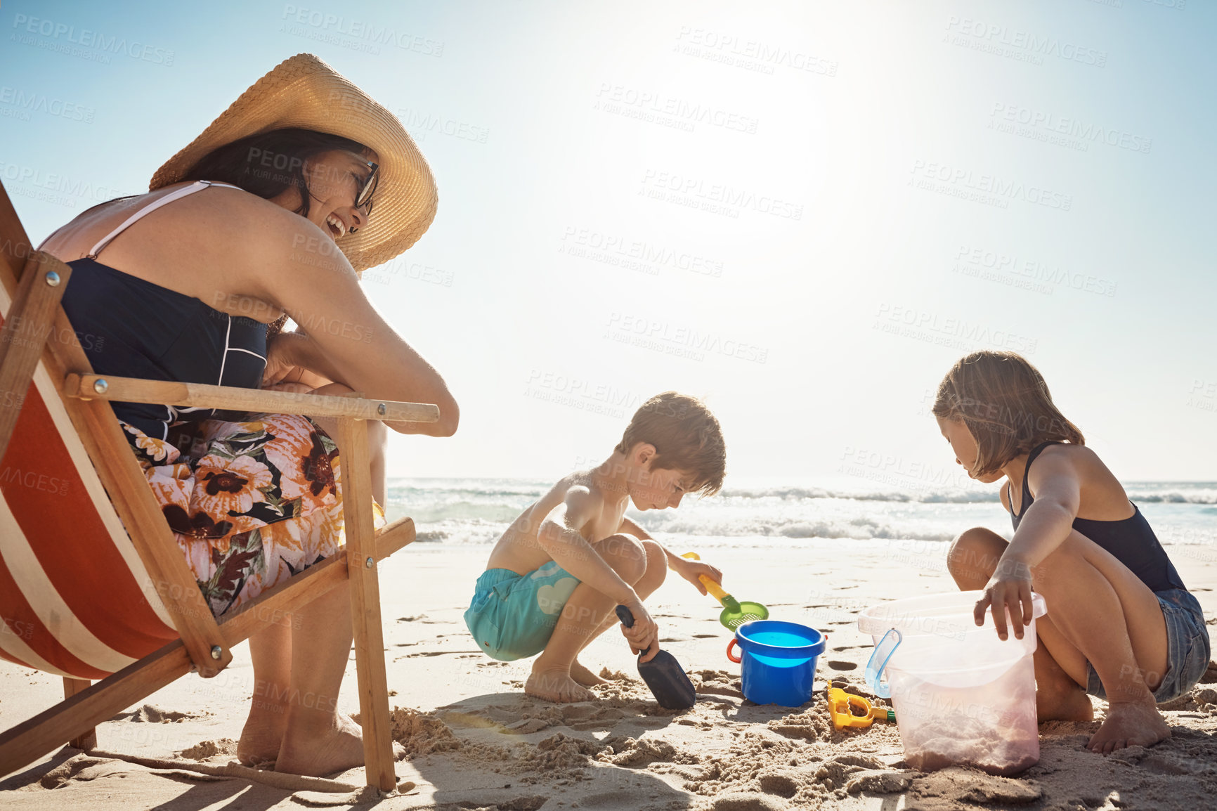 Buy stock photo Mom, children and castle at beach, happy and vacation in summer, playful and container for bonding. Mother, boy and girl with family, holiday and sand with bucket, sunshine and sea with mockup space