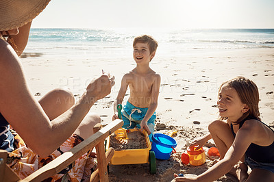 Buy stock photo Shot of a happy brother and sister having fun with their mother at the beach