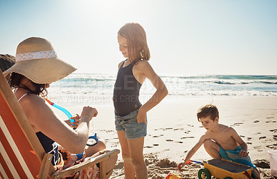 Buy stock photo Shot of a young woman putting snorkelling goggles on her daughter at the beach
