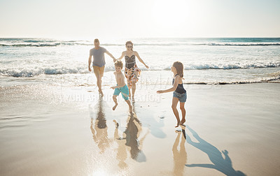 Buy stock photo Shot of an affectionate young family enjoying a day at the beach