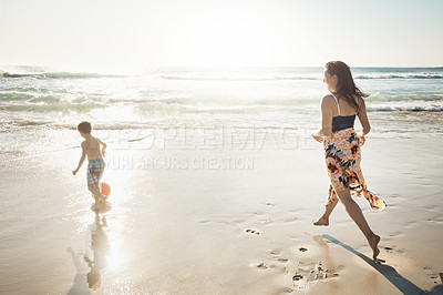Buy stock photo Shot of a young woman spending the day at the beach with her son