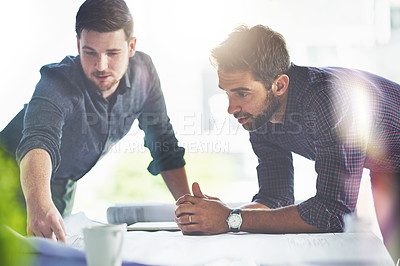 Buy stock photo Shot of two young designers working on blueprints in an office
