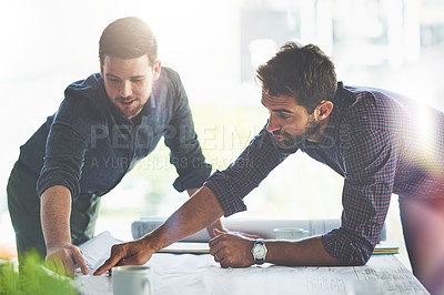 Buy stock photo Shot of two young designers working on blueprints in an office