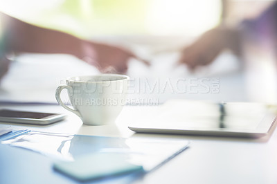 Buy stock photo Shot of a teacup on a table with two businessmen working in the background