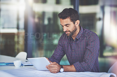 Buy stock photo Shot of a handsome young businessman using a digital tablet in an office