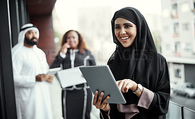 Buy stock photo Cropped shot of an attractive young businesswoman dressed in Islamic traditional clothing using a tablet on her office balcony