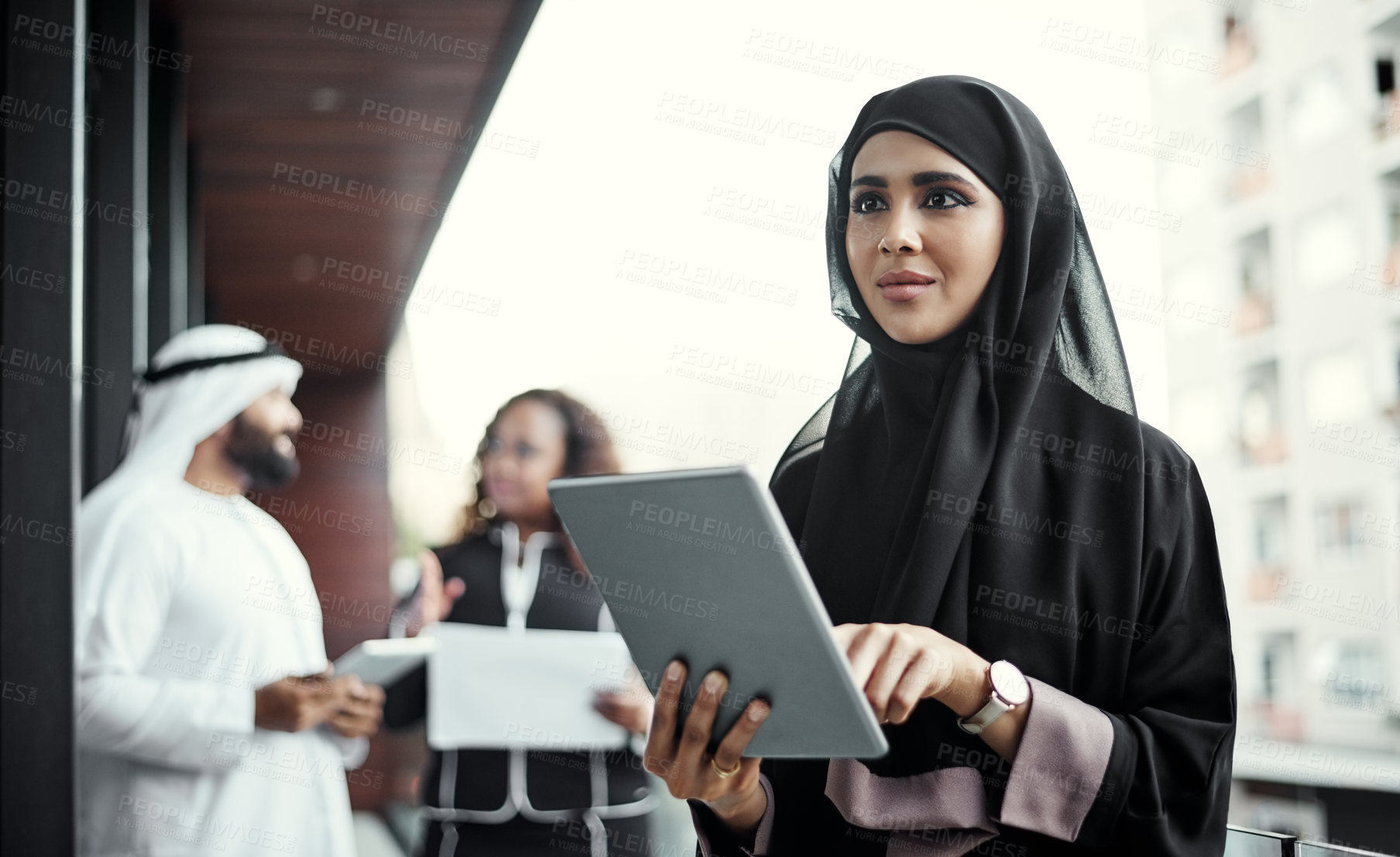 Buy stock photo Cropped shot of an attractive young businesswoman dressed in Islamic traditional clothing using a tablet on her office balcony