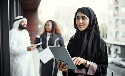 Buy stock photo Cropped shot of an attractive young businesswoman dressed in Islamic traditional clothing using a tablet on her office balcony