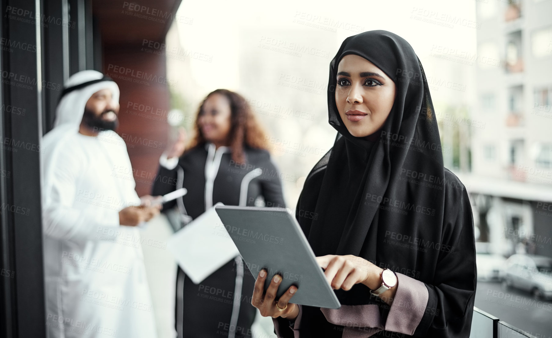 Buy stock photo Cropped shot of an attractive young businesswoman dressed in Islamic traditional clothing using a tablet on her office balcony