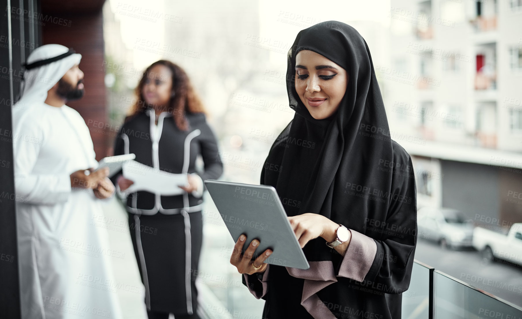 Buy stock photo Cropped shot of an attractive young businesswoman dressed in Islamic traditional clothing using a tablet on her office balcony