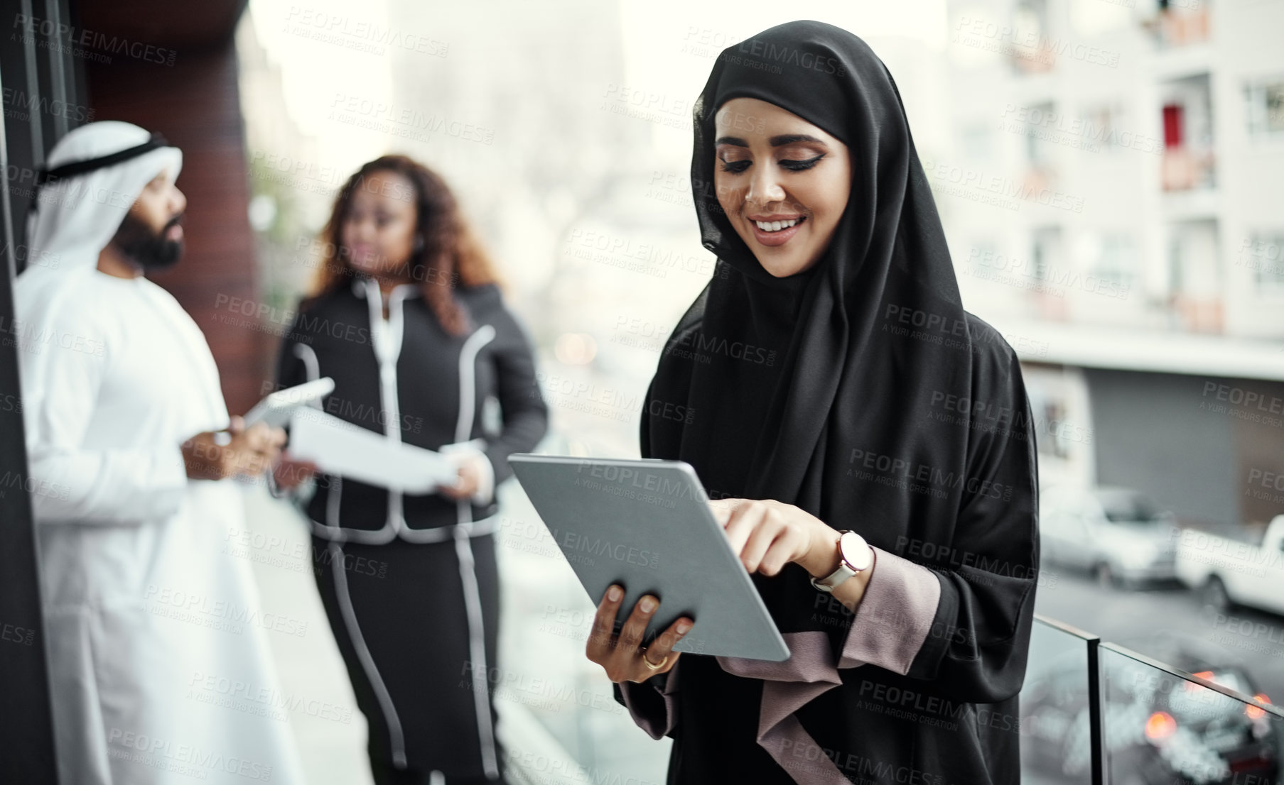 Buy stock photo Cropped shot of an attractive young businesswoman dressed in Islamic traditional clothing using a tablet on her office balcony