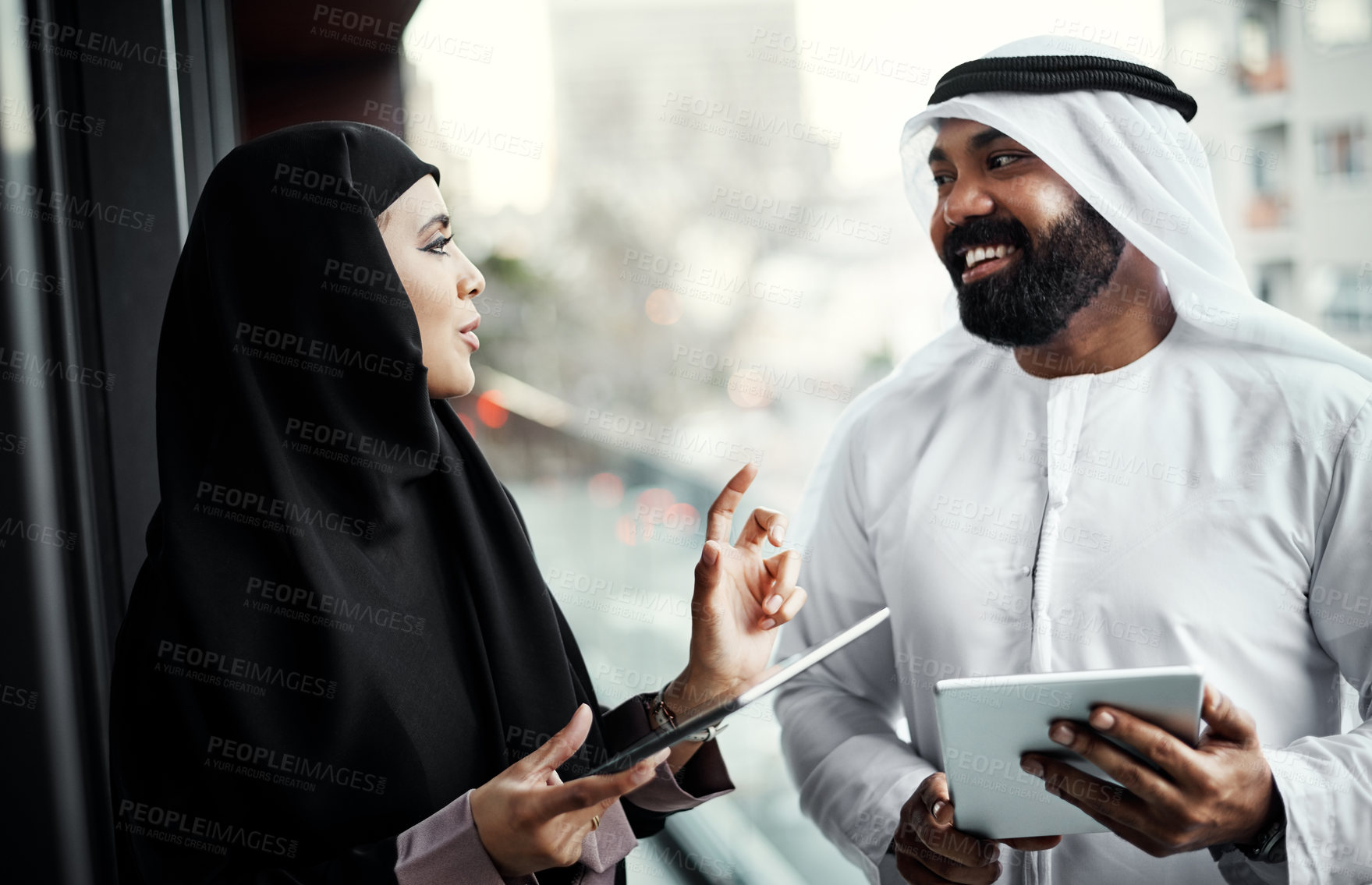 Buy stock photo Cropped shot of two young businesspeople dressed in Islamic traditional clothing using their tablets on the office balcony