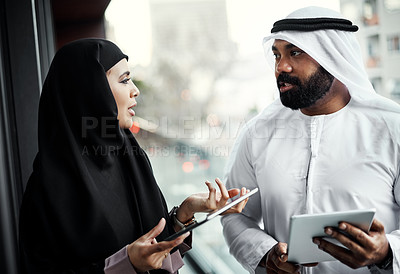 Buy stock photo Cropped shot of two young businesspeople dressed in Islamic traditional clothing using their tablets on the office balcony