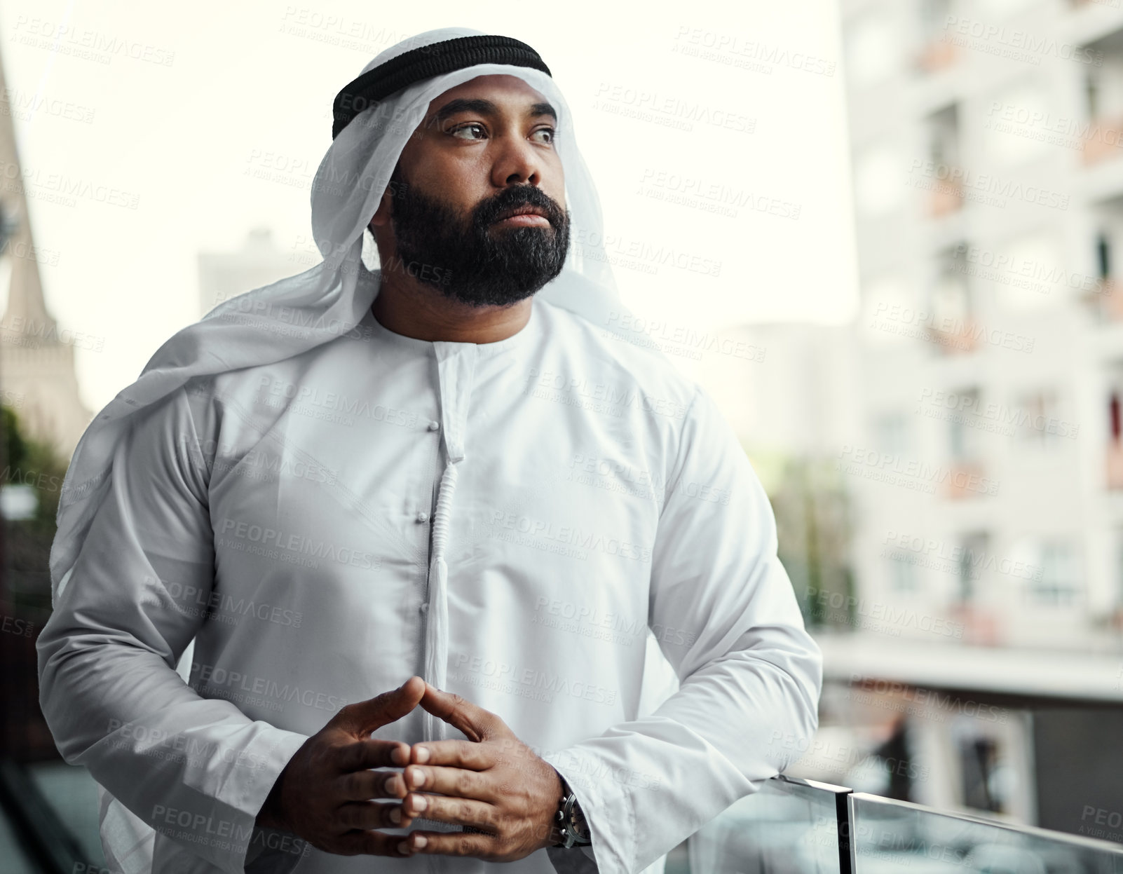 Buy stock photo Cropped shot of a businessman dressed in traditional Islamic clothing working on his office balcony