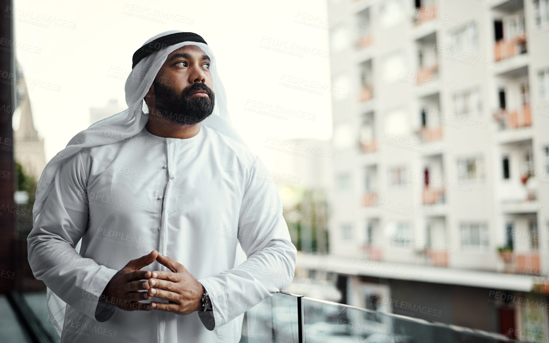 Buy stock photo Cropped shot of a businessman dressed in traditional Islamic clothing working on his office balcony