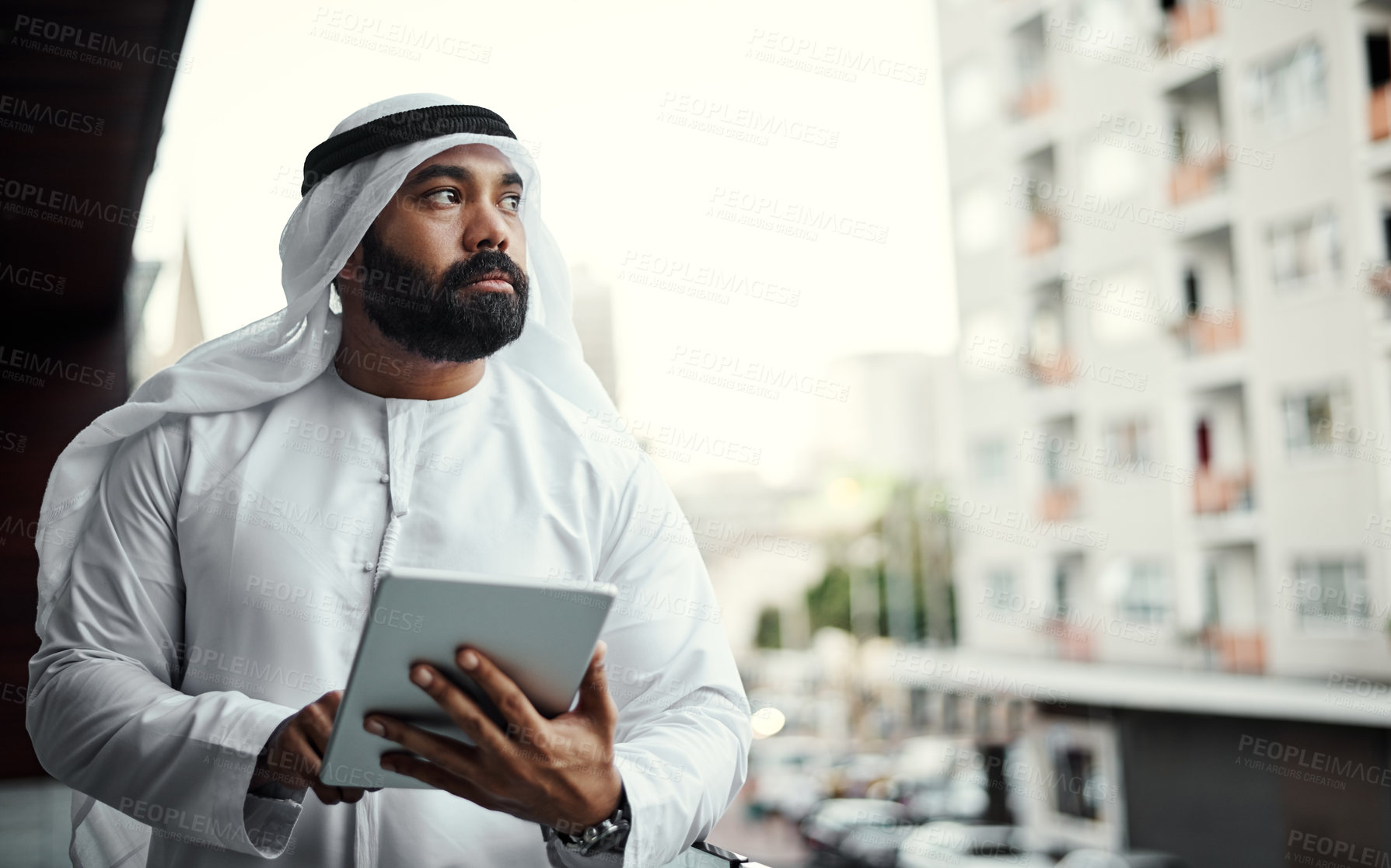 Buy stock photo Cropped shot of a businessman dressed in traditional Islamic clothing working on his office balcony