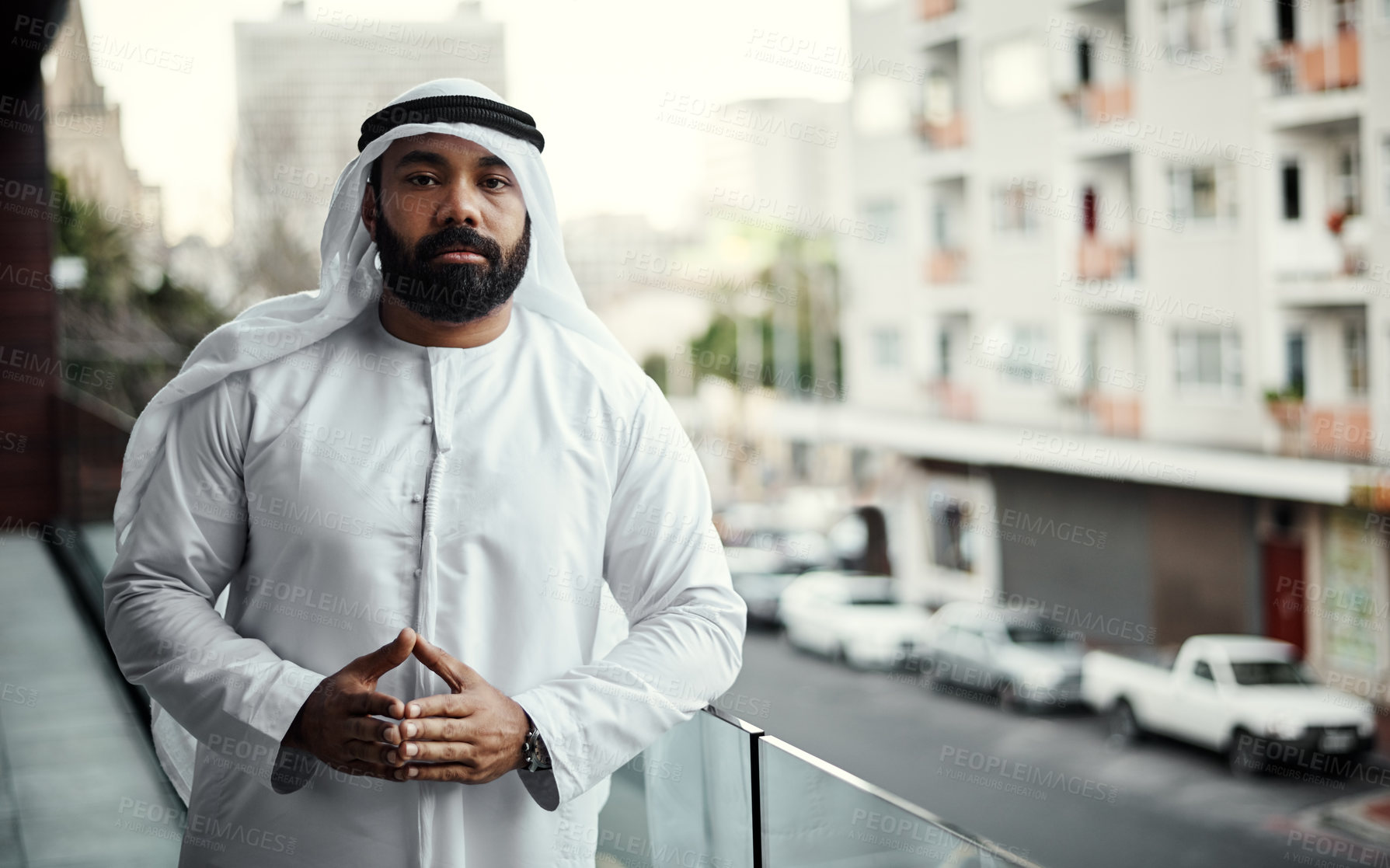 Buy stock photo Cropped portrait of a businessman dressed in traditional Islamic clothing working on his office balcony