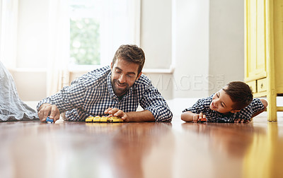 Buy stock photo Shot of a young boy and his father playing with cars on the floor
