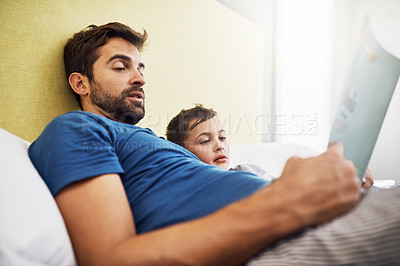 Buy stock photo Shot of a young man reading a book with his son at home