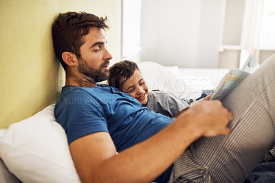 Buy stock photo Shot of a young man reading a book with his son at home