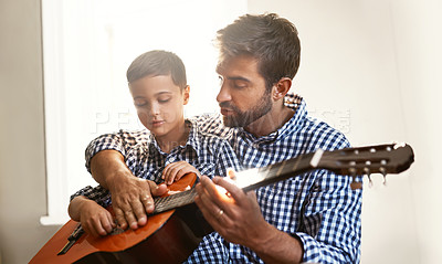 Buy stock photo Shot of a young man playing the guitar with his son at home