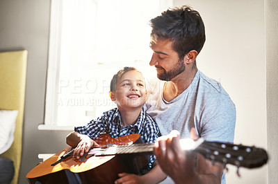 Buy stock photo Shot of a young man playing the guitar with his son at home