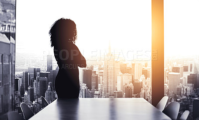 Buy stock photo Silhouetted shot of a young businesswoman looking at a cityscape from an office window