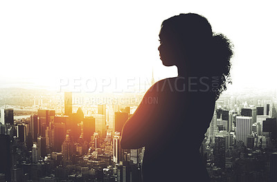 Buy stock photo Silhouetted shot of a young businesswoman looking at a cityscape from an office window