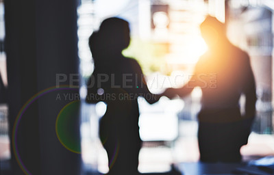Buy stock photo Defocused shot of two businesspeople shaking hands in an office