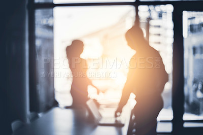 Buy stock photo Defocused shot of two businesspeople working in an office