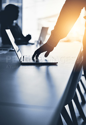 Buy stock photo Silhouetted shot of an unrecognizable businessman using a laptop in an office