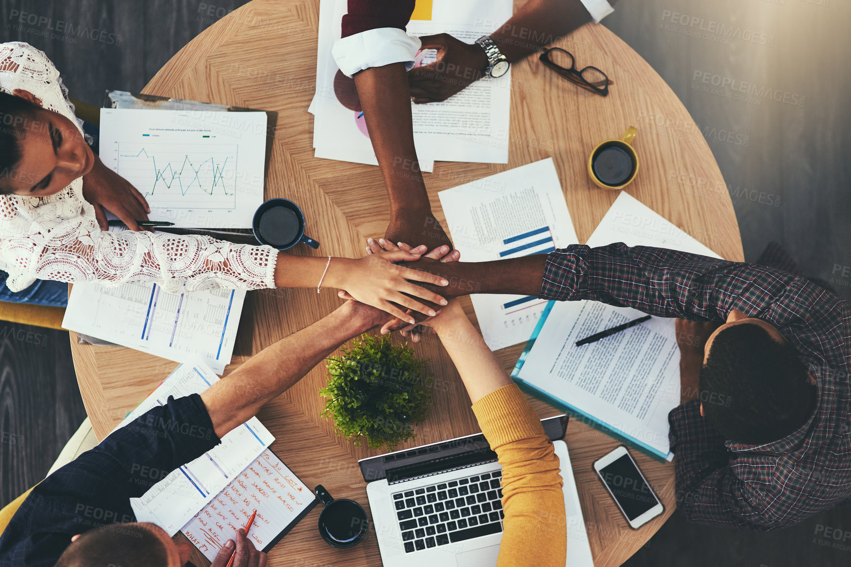 Buy stock photo High angle shot of a group of businesspeople joining their hands in solidarity during a meeting in a modern office