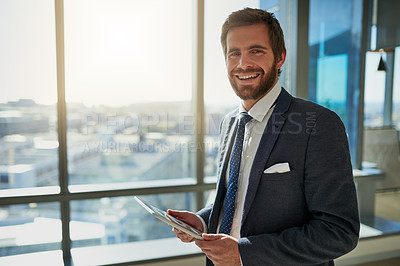 Buy stock photo Cropped portrait of a handsome young businessman using a tablet in his office
