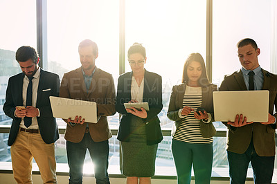 Buy stock photo Cropped shot of a group of businesspeople using wireless devices while standing in the office