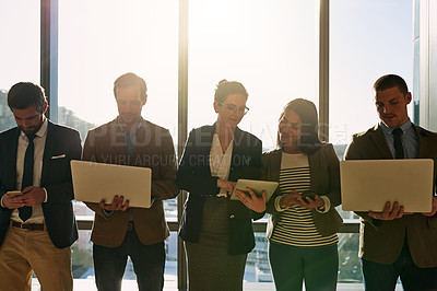 Buy stock photo Cropped shot of a group of businesspeople using wireless devices while standing in the office