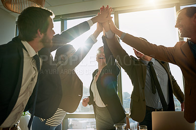 Buy stock photo Cropped shot of a group of businesspeople high fiving while standing in a huddle
