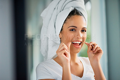 Buy stock photo Shot of an attractive young woman flossing her teeth at home