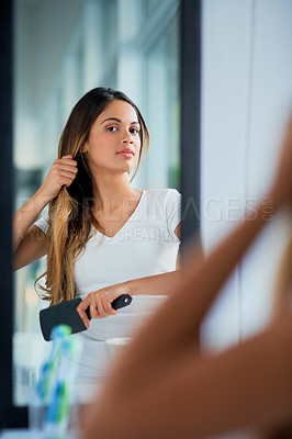 Buy stock photo Shot of an attractive young woman brushing her hair in the bathroom
