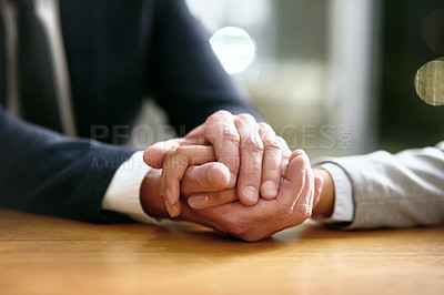 Buy stock photo Cropped shot of a businessman and businesswoman compassionately holding hands at a table