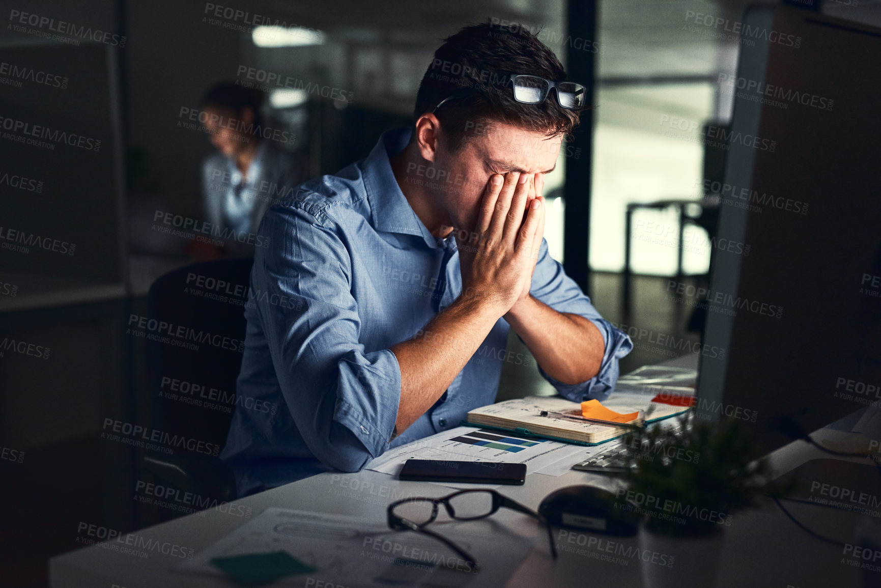 Buy stock photo Shot of a young businessman working late at night in a modern office