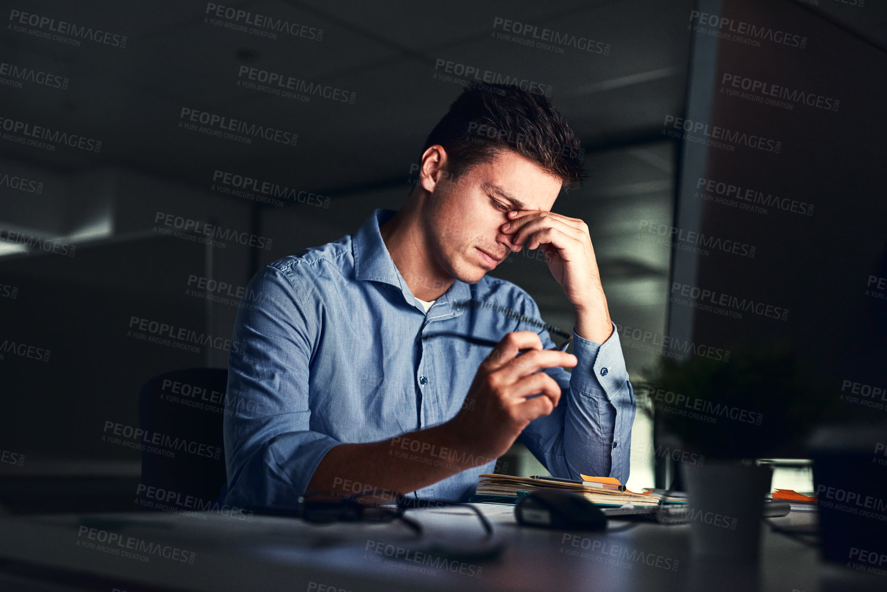 Buy stock photo Shot of a young businessman working late at night in a modern office