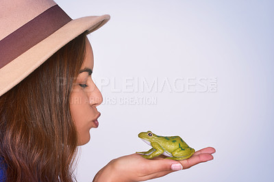 Buy stock photo Face, kiss and profile of woman with frog in studio on blue background for hope, magic or wish. Fantasy, love or storytelling and person holding toad in hands to imagine fairytale with eyes closed